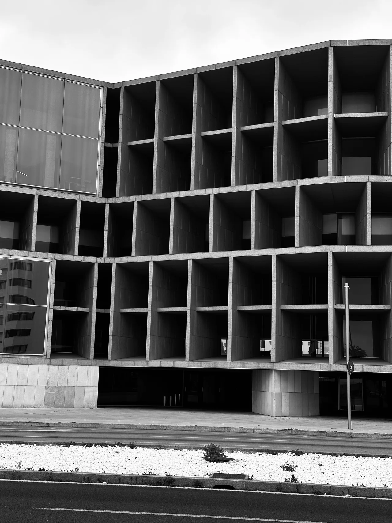 Fachada contemporánea de hormigón con una retícula de pilares y sombras